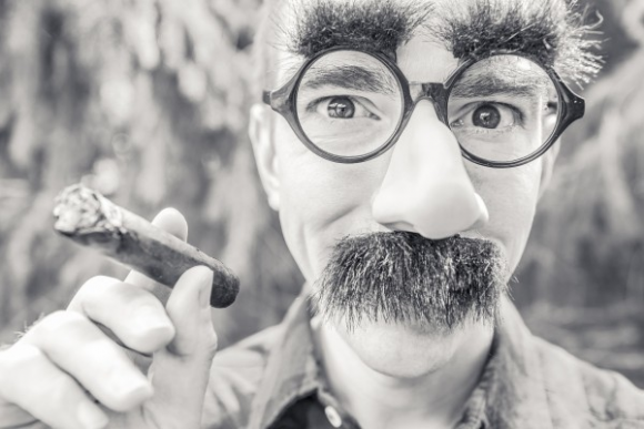 black-and-white-portrait-of-man-smoking-cigar-and-wearing-artificial-beard-and-eyebrows-1